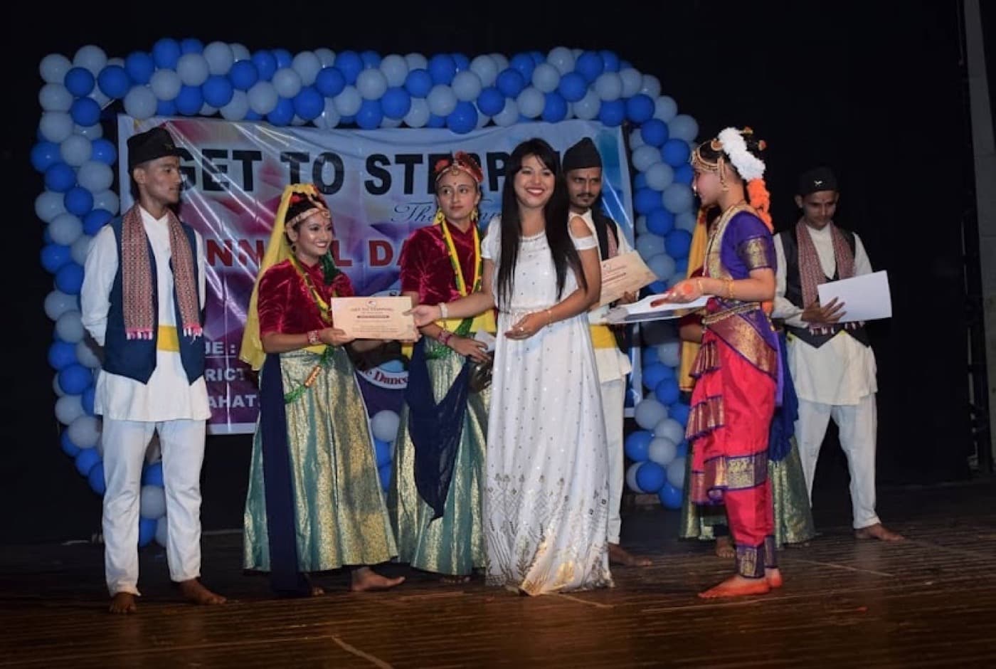Students in traditional dress receiving certificates on stage